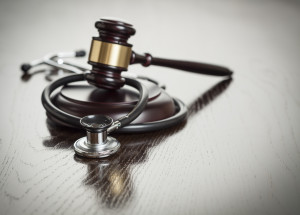 Gavel and Stethoscope on Reflective Wooden Table.